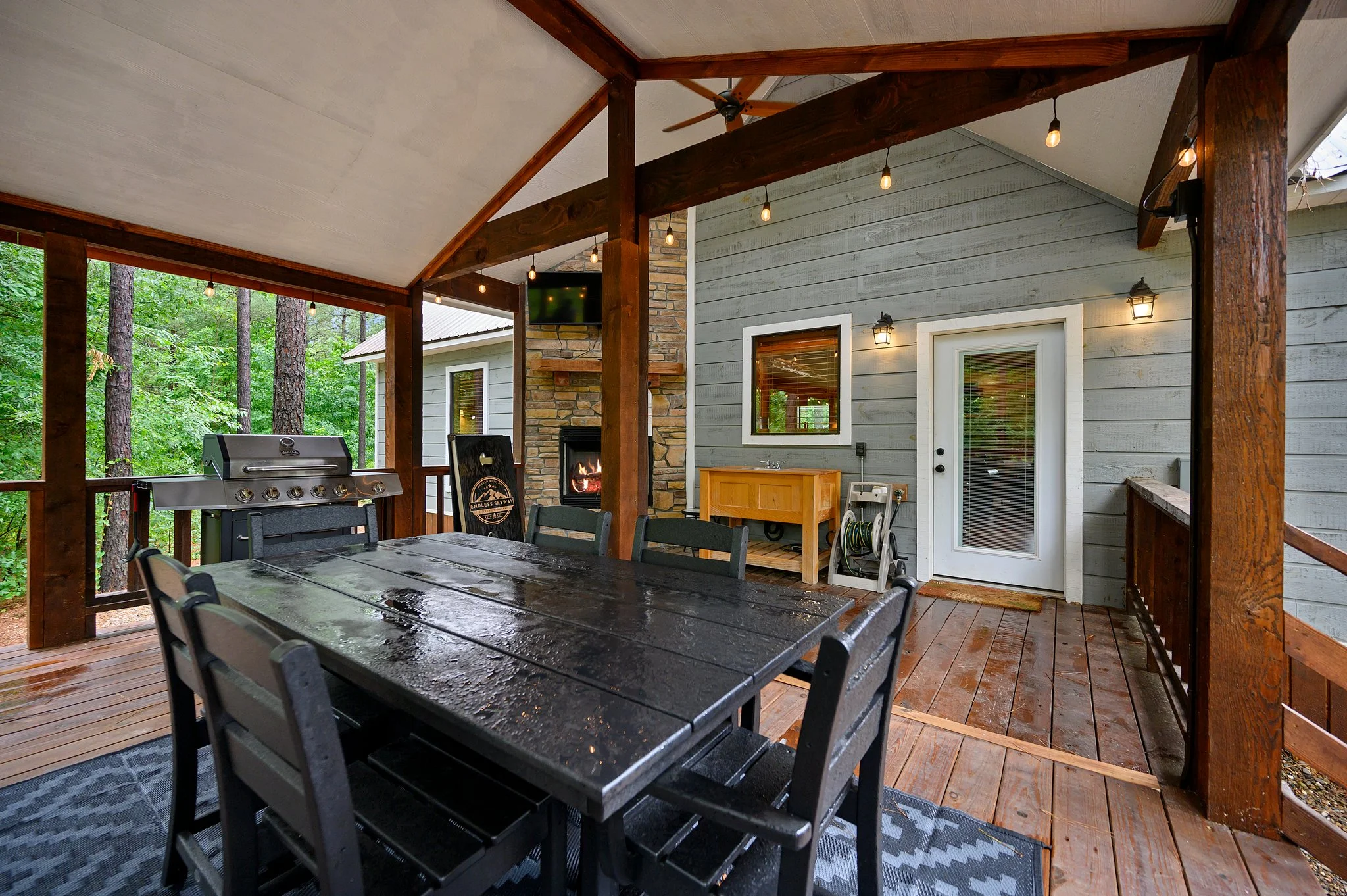 Covered patio with outdoor dining, fireplace and grill at Endless Skyway Cabin, a Broken Bow Oklahoma hotels alternative