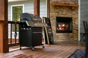 Rustic patio with stainless steel gas grill and lit stone fireplace, a zip lining Broken Bow, OK cabin getaway at Endless